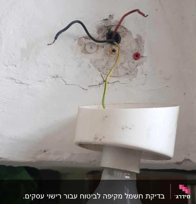 חוטי חשמל חשופים ליד נורה תלויה